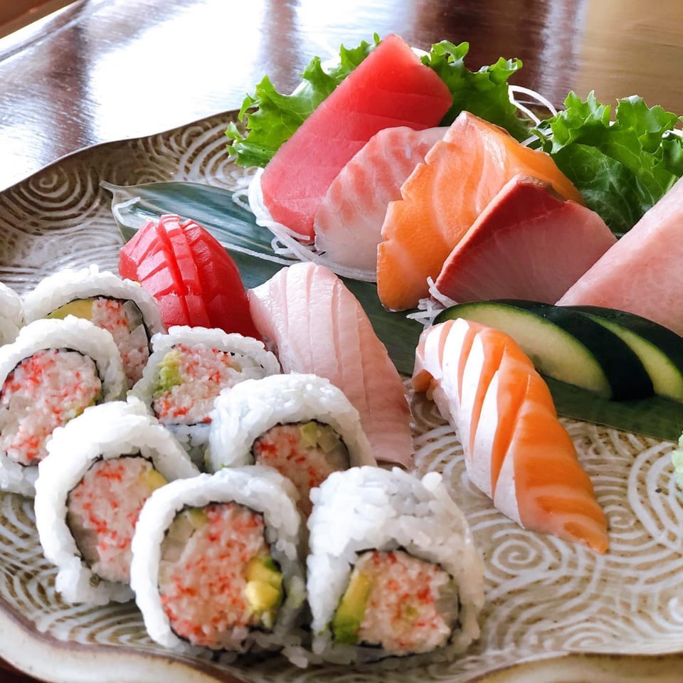 A platter of Kanpai Izakaya sushi, sashimi, and California rolls with tuna, salmon, and cucumber.